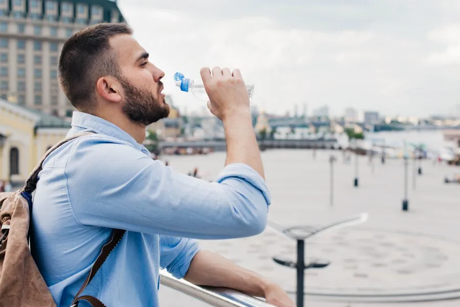 vista-lateral-viajero-masculino-beber-agua-botella-plastico_23-2148203119